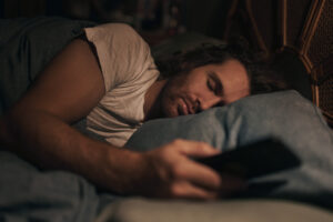 Mann mit Handy im Bett