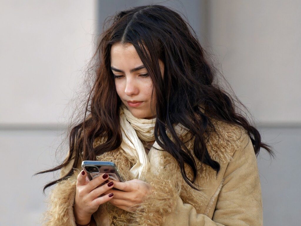 Junge Frau schaut auf Smartphone.